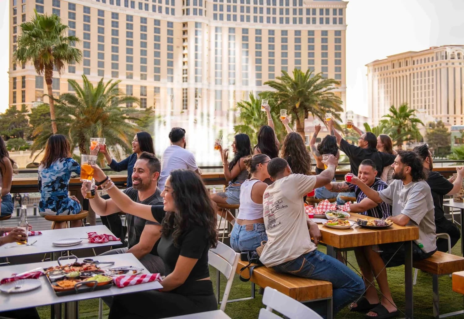 Guests raising drinks on the Beer Park patio, with the Bellagio behind them.
